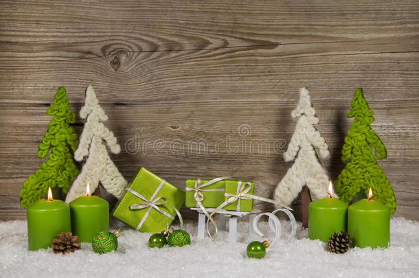 四支绿色燃烧的圣诞蜡烛，上面有礼物和树