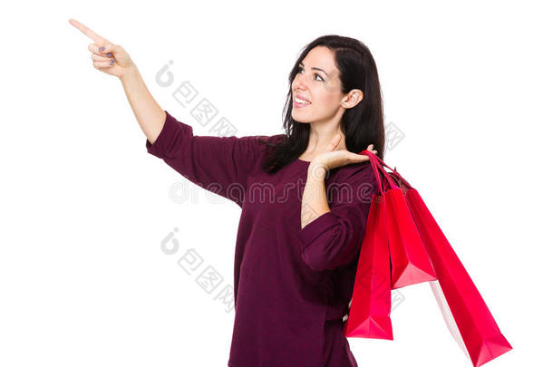 黑发女人拿着购物袋，手指指着