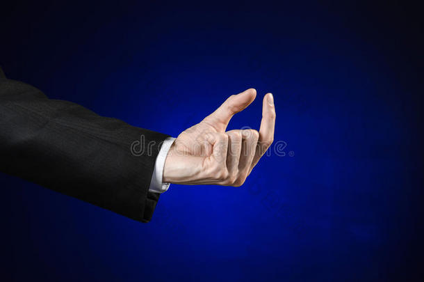 商人和手势主题：一个穿着黑色西装和白色衬衫的男人在一个孤立的深<strong>蓝色</strong>背景上<strong>展示</strong>手势
