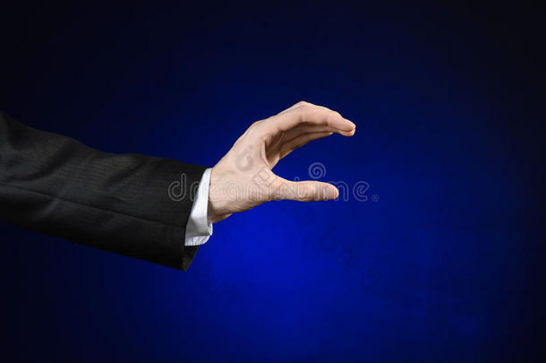 商人和手势主题：一个穿着黑色西装和白色衬衫的男人在一个孤立的深<strong>蓝色</strong>背景上<strong>展示</strong>手势