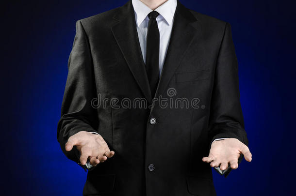 商人和手势主题：一个穿着黑色西装和白色衬衫的男人，用手在深<strong>蓝色</strong>的背景上<strong>展示</strong>手势