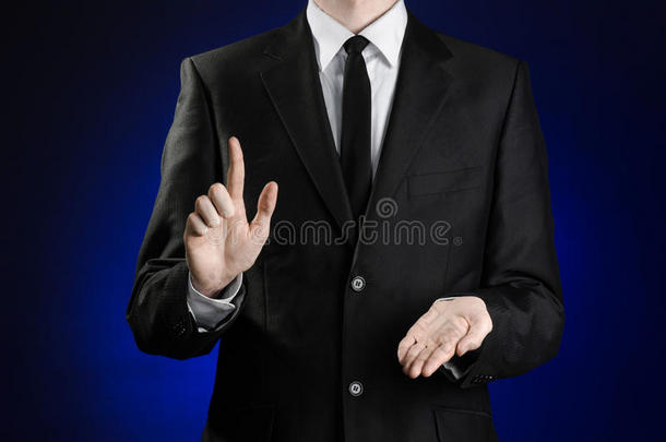 商人和手势主题：一个穿着黑色西装和白色衬衫的男人，用手在深<strong>蓝色</strong>的背景上<strong>展示</strong>手势