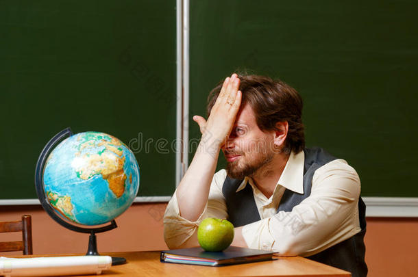 地理老师坐在地球仪前面。