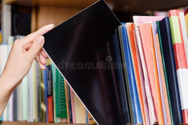 特写手把一台平板电脑放在图书馆的书架上