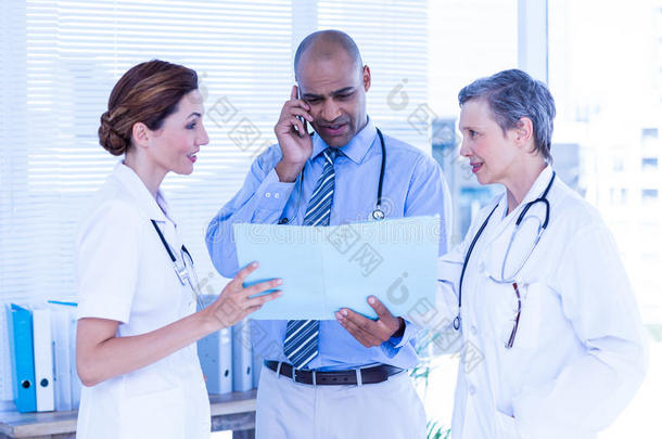 集中的医生在打电话时向他的同事展示文件