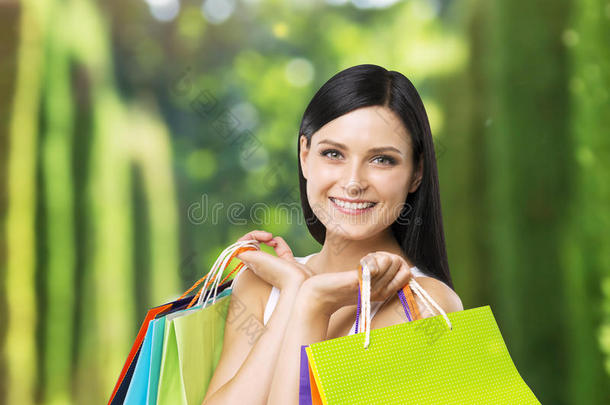 一位快乐的年轻女士，从高档商店里拿着五颜六色的购物袋。
