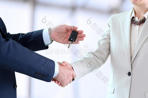 汽车推销员把一辆<strong>新</strong>车的钥匙交给一个年轻的商人