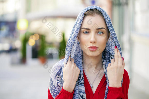 美丽的年轻女人戴着蓝色围巾在夏天的街道城市