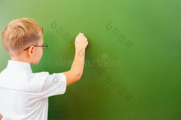一年级的小学生在教室里用粉笔在黑板上写字