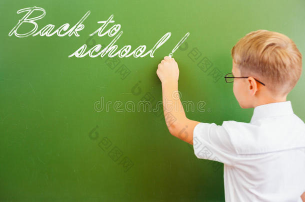 一年级的小学生在教室里用粉笔在黑板上写字