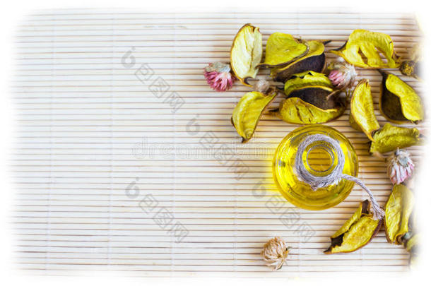 竹垫背景上有干花花瓣的精油或化妆品油瓶