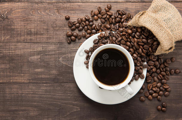 木制背景上的咖啡杯和咖啡豆。 上面的风景。