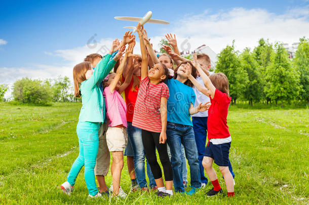一群孩子在大白色飞机玩具后伸手