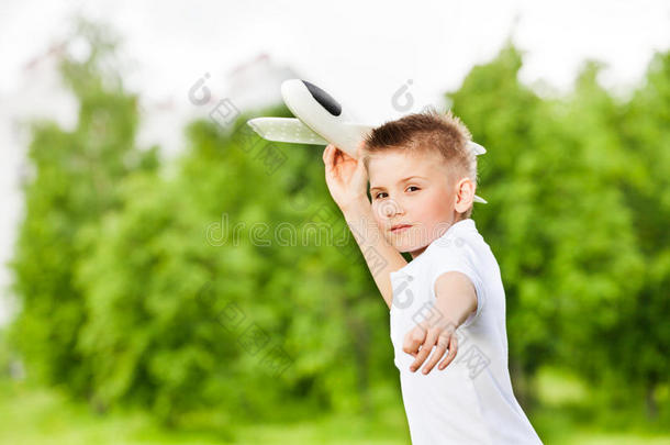 在绿色草地上拿着白色<strong>飞机玩具</strong>的男孩