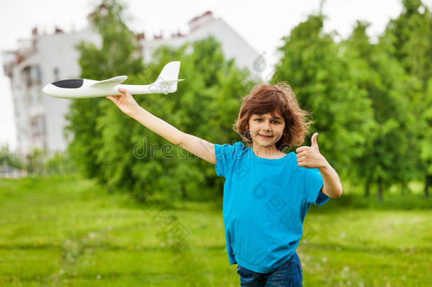 男孩竖起大拇指拿着白色飞机玩具