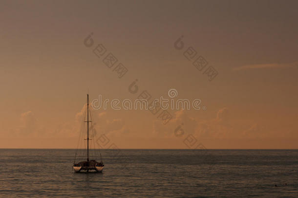 日落时在平静的海面上的双体帆船