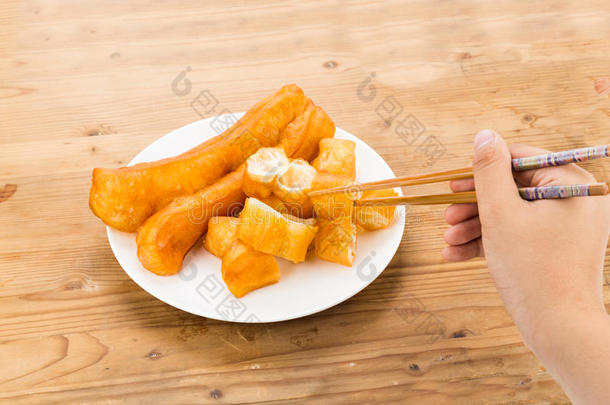 筷子伸手拿一块你的饺子，或油炸面包棒在木桌上