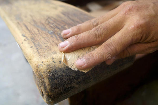 用砂纸清洁旧沙发手臂的手部细节