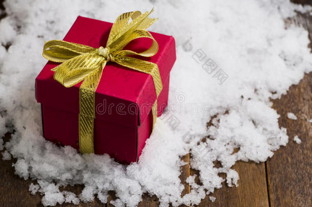 圣诞礼物盒，雪上有金色丝带蝴蝶结