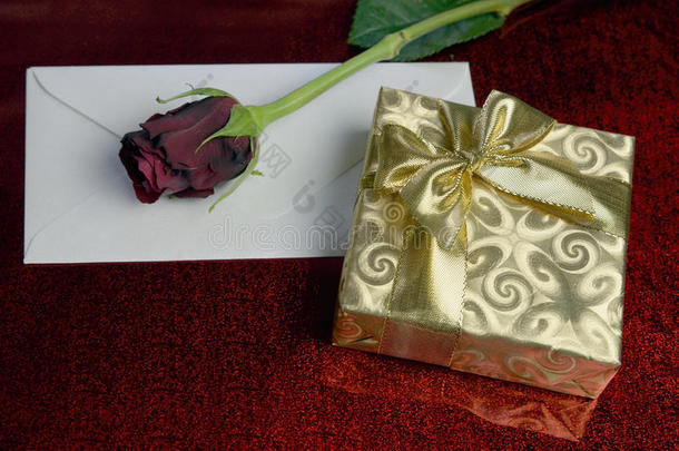 用金纸、红玫瑰和一个空白信封包裹的礼物