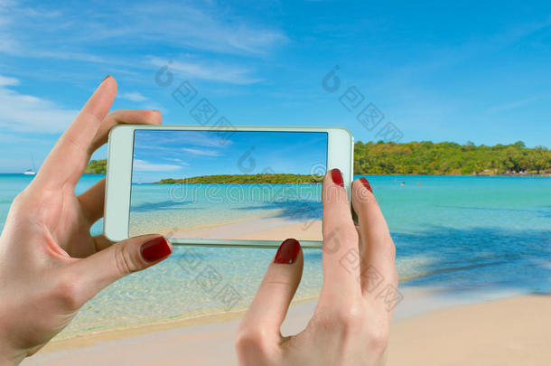 一个女人在海滩上的地平线上用智能手机相机拍照的背景