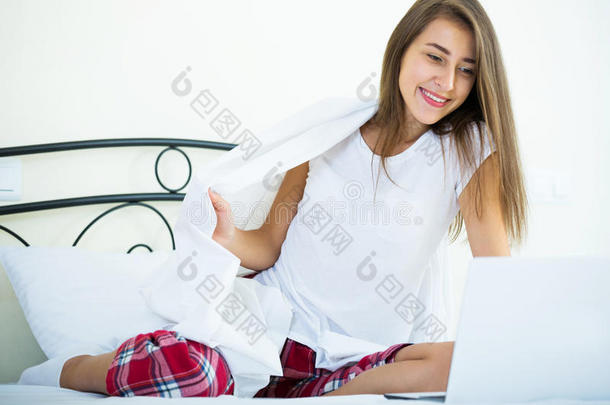 开朗的学生女孩在床上学习笔记本电脑