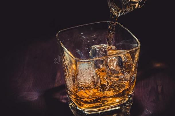 酒保将威士忌倒在木桌上的玻璃杯里，温馨的气氛，古老的西式风格，用威士忌放松的时光