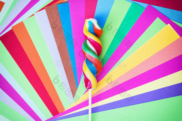 彩色扭曲的甜蜜棒棒糖与彩色纸