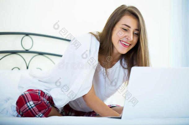 开朗的学生女孩在床上学习笔记本电脑