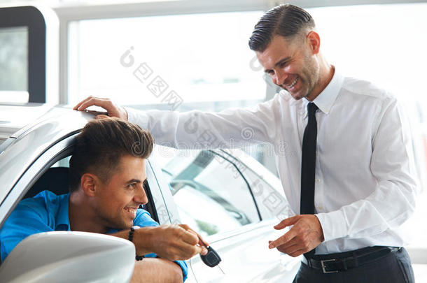 汽车推销员在陈列室把新的汽车钥匙交给顾客