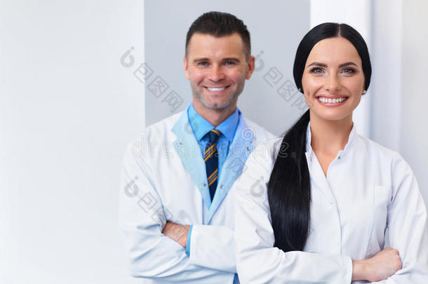 牙科诊所的牙医小组。 两个微笑的医生在他们的工作