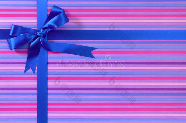 蓝色圣诞节或生日礼物丝带蝴蝶结在糖果条纹包装纸背景