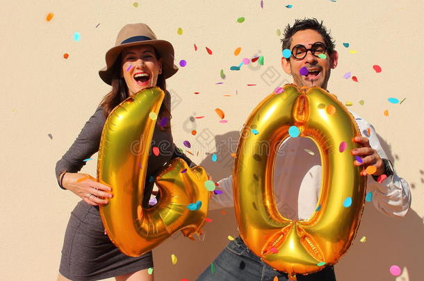 这对欢快的夫妇用金色的大气球和五颜六色的小纸片在空中庆祝四十年的生日