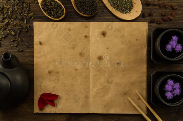 黑色茶壶，两个杯子，<strong>采茶</strong>，花，木制背景上的旧空白打开书。 菜单，食谱