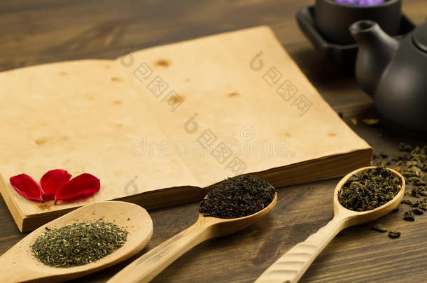 黑色茶壶，杯子，采茶，花，木制背景上的旧空白打开书。 菜单，食谱
