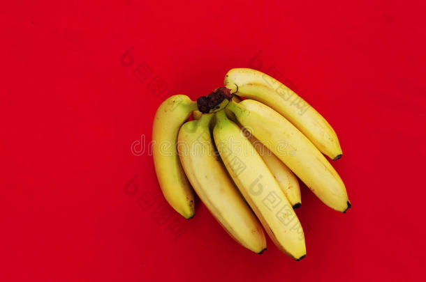 红色背景上的一堆香蕉。 新鲜有机香蕉，厨房桌子上的新鲜香蕉