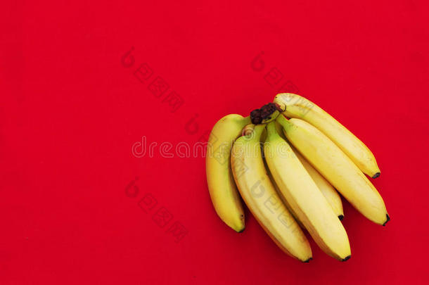 红色背景上的一堆香蕉。 新鲜有机香蕉，厨房桌子上的新鲜香蕉