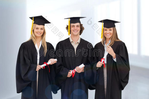 三名学生穿着研究生长袍拿着文凭的复合形象