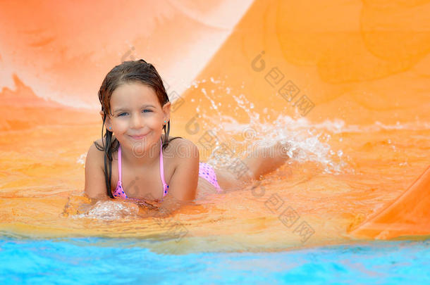 可爱的蹒跚学步的女孩在水上滑梯在水上