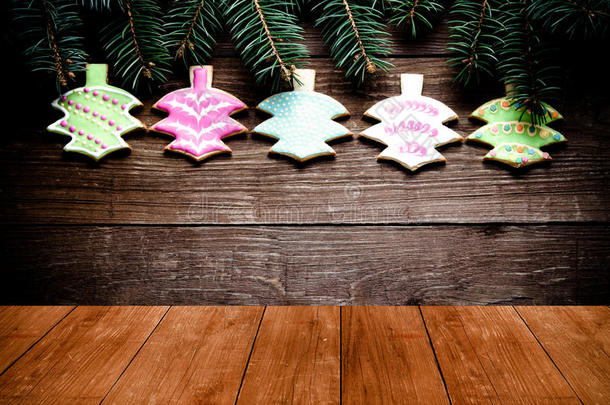 姜饼自制饼干与糖霜和圣诞树树枝在木墙上的旧深色木制桌子或木板。 新年