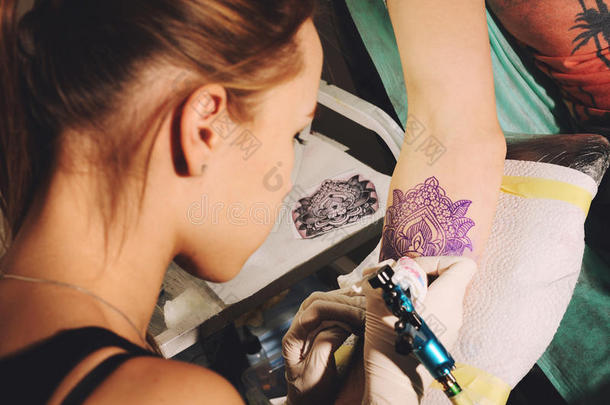 女孩纹身艺术家用素描在一只手上做纹身，以对抗未来纹身的蓝色肖像。