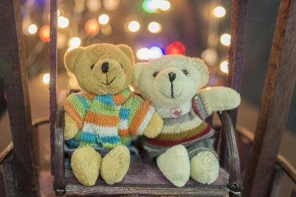 可爱的两只娃娃熊。 一对可爱的泰迪熊坐在木摆上，背景是波克光。 泰迪熊穿冬天的套房。 拥抱