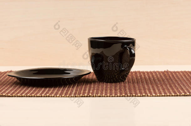 红茶杯站在<strong>桌</strong>子上的黑色盘子附近。