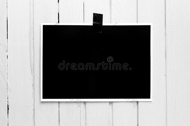 空白的黑色海报挂在白色木板墙上的胶带上。