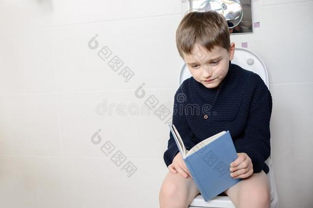 孩子坐在马桶上看书