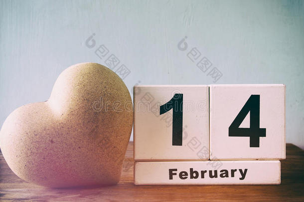 2月14日木制老式日历旁边的心木桌子。 陈年过滤