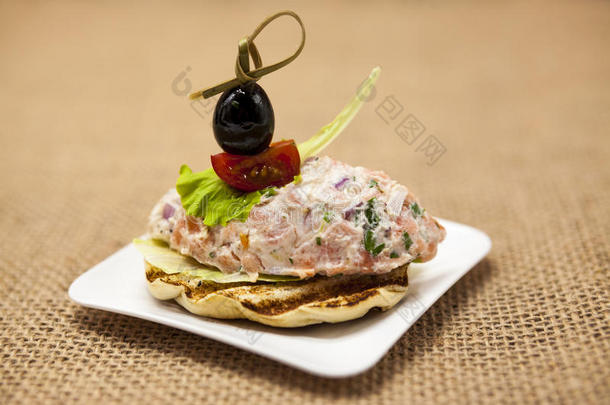 面包上的新鲜西班牙丝瓜熏挪威鲑鱼，配黑色橄榄黄油、草药和洋葱。 一个<strong>优秀</strong>的背景f