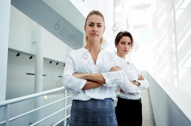 有经验的女企业家与合作伙伴在现代白色办公室内部摆姿势，看上去自信，