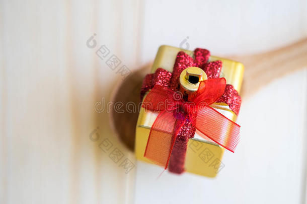 木制勺子上有红色丝带礼物的金色盒子