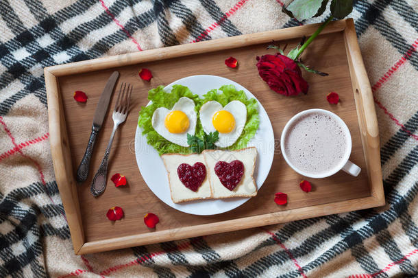 早餐在床上<strong>有</strong>心形鸡蛋，烤面包，果酱，咖啡，玫瑰和花瓣。 情人节<strong>惊喜</strong>。